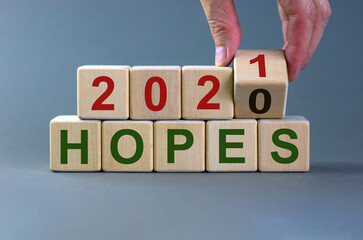 2021 new year hopes symbol. Male hand flips a wooden cube and changes the inscription 'Hopes 2020' to 'Hopes 2021'. Beautiful grey background, copy space. Business and 2021 new year concept.