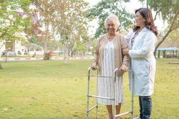 Doctor help and care Asian senior or elderly old lady woman use walker with strong health while walking at park in happy fresh holiday.