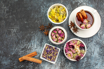 top view of herbal tea with cinnamon and drry flowers on grey background