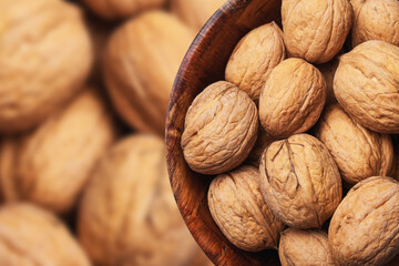 Walnuts background. Walnuts in wooden bowl. Whole nuts in shells in round container with empty copy space for graphic design text. Healthy food ingredient texture.