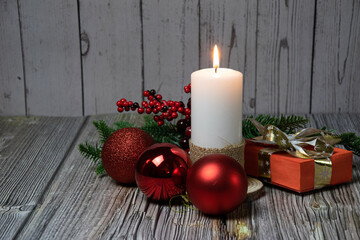Wax candle with red balls, fir branches and gifts