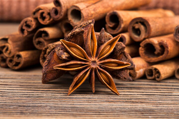 Stack of cinnamon sticks with star anise spices on a wooden background. Macro photography of spices.