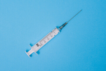 Medical syringe isolated on a blue background. Disposable plastic syringe for treatment. Vaccination and Immunization. Antibiotic treatment. Health and medicine