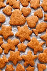 Christmas gingerbread cookies in various shapes on baking paper top view. Gingerbread background