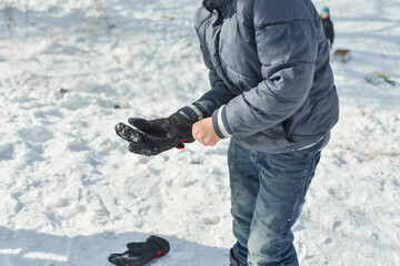 Fototapeta na wymiar The boy tries to put a glove on his hand in winter.