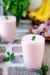 Strawberry, milk and banana smoothie or milkshake in a glass, decorated with a mint leaf. Selective focus on mint. Healthy food or snacks, close-up