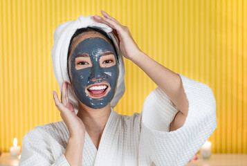 A young Asian woman is masking her face with black mud