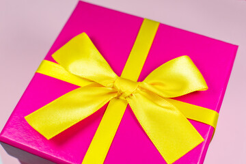 Present box with yellow bow on pink background. Birthday parties. Sale and discount. Christmas shopping ideas. Special offer. Copy space. Black Friday concept.
