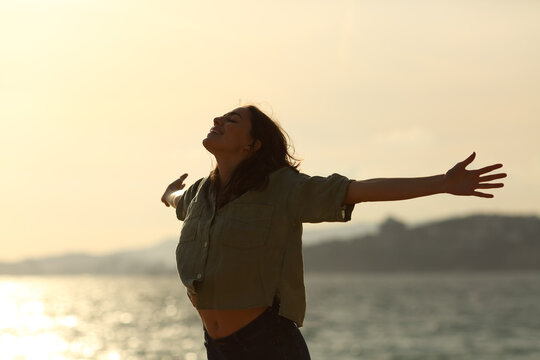 Silhouette Of Excited Woman Stretching Arms On The Beach