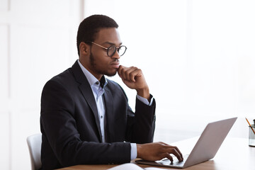 Serious african american manager working with laptop in office