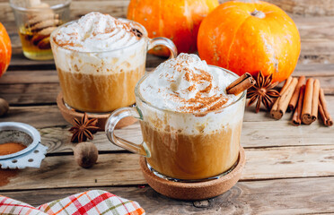 Pumpkin spiced latte or coffee in a glass on a vintage table. Autumn or winter hot drink.