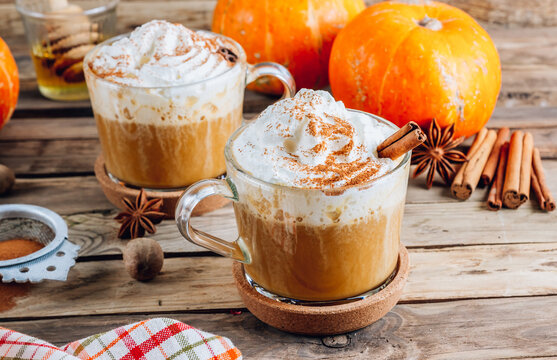 Pumpkin spiced latte or coffee in a glass on a vintage table. Autumn or winter hot drink.