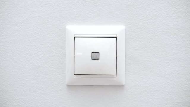 White switch on a light wall. Switch the button to turn on the light in the room. Turning on and off the lighting in the room. Close-up
