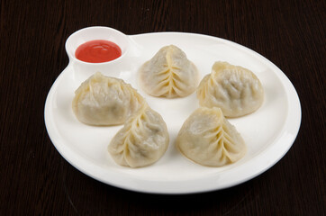manti, dumplings, asian traditional cuisine, in white plate on wooden background