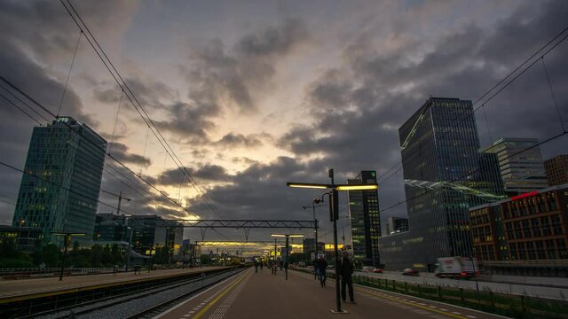 Amsterdam, the Netherlands - oktober 17th 2019: Time lapse of rush hour at the Amsterdam Zuidas train station with cars and trains passing by and commuters walking from the platform to work in offices
