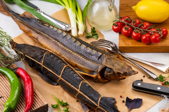 Smoked seafood. Smoked sturgeon and sterlet on parchment with vegetables. Appetizer