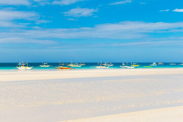 Tropical beach and beautiful sea with boats. Blue sky with clouds in the background.