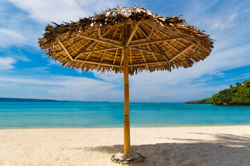 Straw sun umbrella on the tropical sand beach on Boracay island, Philippines. Summer vacation concept.