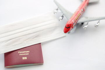 Safe travel during the virus covid-19 pandemic . Airplane model with face mask, passport, isolated on white background, top view. Nobody, no people, space for text on left side, Selective focus. 