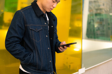 Asian young adult holding cellphone.