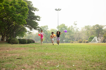 Group of kids running in the spring field at public park with balloon. Movement and blurry too...