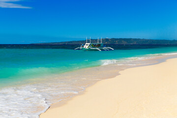 Tropical beach and beautiful sea with boats on Boracay island, Philippines. Blue sky with clouds in the background.