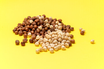 Full and halfs of hazelnuts on yellow background. Isolated
