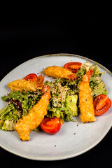 Salad with chicken fillet, lettuce and vegetables on a black background