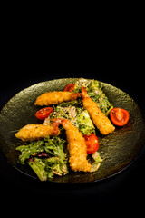 Salad with chicken fillet, lettuce and vegetables on a black background