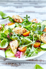 Salad with Chicken Breast, Cherry Tomatoes, Cucumber, Rocket and fresh Basil. Bright wooden background. Close up. 