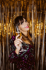 .Beautiful woman dressed for New Years Eve in a sparkling dress. Fun and festive attitude. Making a toast with a glass of champagne