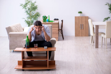 Young male alcoholic drinking whiskey at home