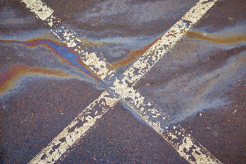 Gas stain on wet asphalt in the car park caused by a leak under a car or truck