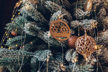 Christmas tree decorated with wooden ornaments, garland and golden balls. New year holiday seasonal decor