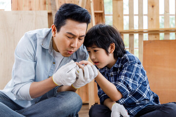 Asian father relief pain on son finger which get splinter of the wood.