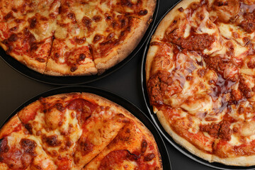 Three pizzas on black background viewed from above