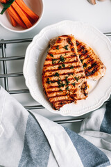 Grilled turkey steak with herbs and spices in a white plate on the table.