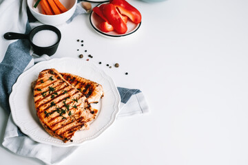 Grilled turkey steak with herbs and spices in a white plate on the table.