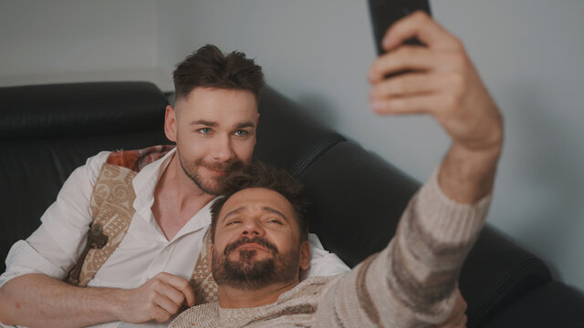 Funny romantic male gay couple using smartphone for video call. High quality photo