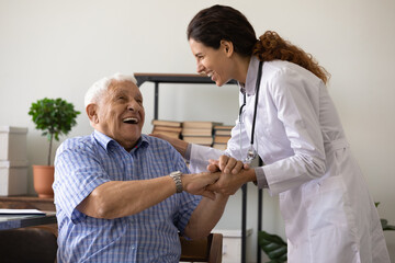 Positive young female nurse have fun laugh and joke with happy elderly male patient at consultation in hospital. Caring woman doctor support cheer and comfort mature man. Good medicine concept. - obrazy, fototapety, plakaty
