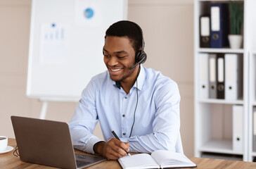 Cheerful black guy crisis manager working in front of laptop