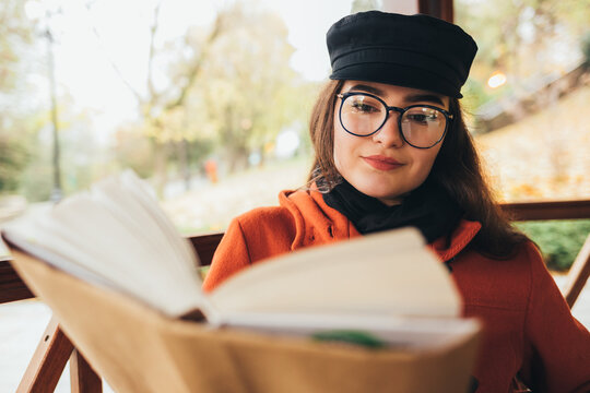 Stylish young woman in coat reading a book