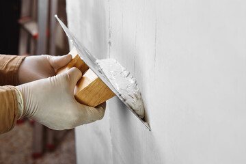 Close up of construction worker hands plastering and smoothing wall with a trowel. House renovation concept. 