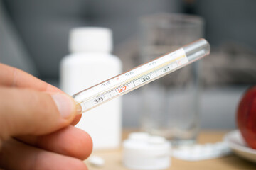 Hand holding mercury thermometer for checking temperature, close-up view