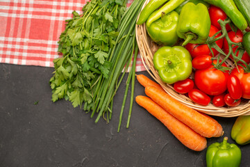 Overhead view of fresh various organic vegetables in a wooden basket on orange stripped towel on dark background