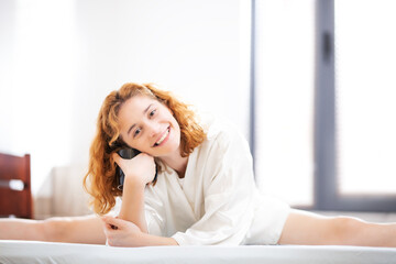Fototapeta premium Happy careless girl at home. Lying in bed drinking coffee or tea in the morning