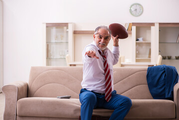 Old male boss employee throwing rugby ball at home