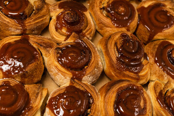 Homemade cinnamon buns with spices and caramel on parchment paper.