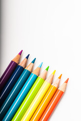 Rainbow of colored pencils lined up against a white background