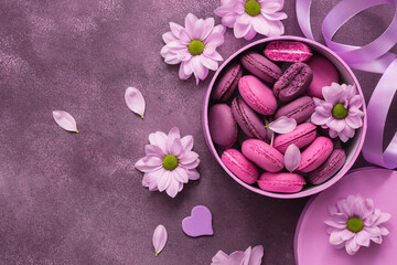 Purple macaroons in a pink box decorated with flowers. Valentine's Day. View from above.